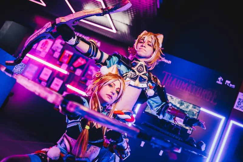 Rapaz de peruca loira e uma moça em cosplay, com arco e espada, sob luz de neon rosa e azul.