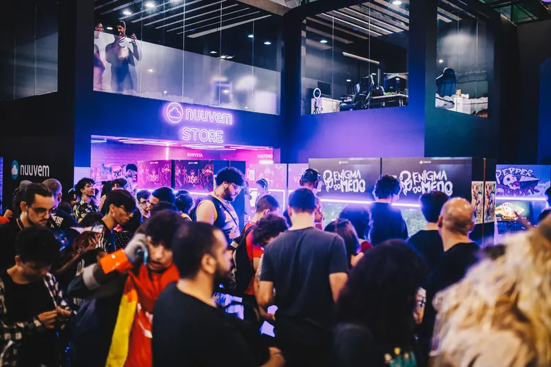 Público aglomerado diante do estande da Nuuvem, com vitrines e letreiros em neon ao fundo.