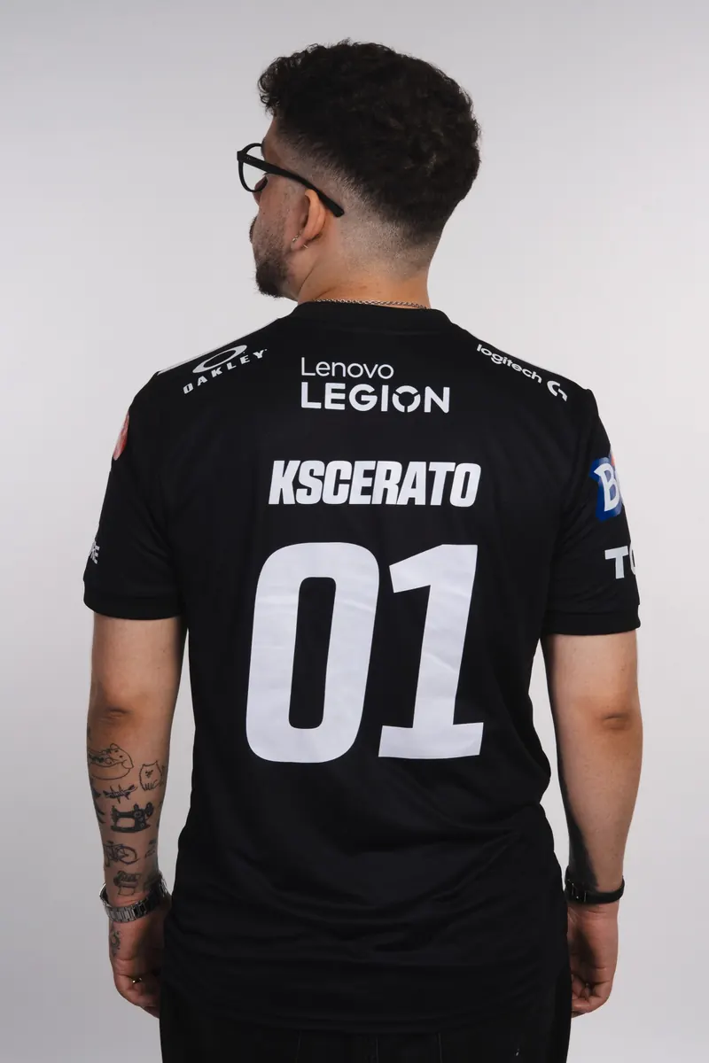 Retrato de costas de jogador de óculos e camisa preta da FURIA com um grande número na parte de trás, em fundo cinza claro.